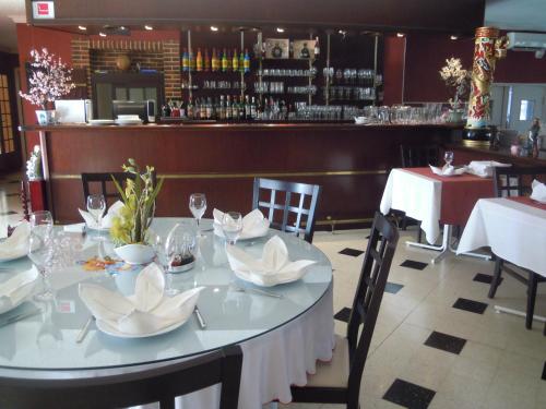 un comedor con una mesa con sillas y un bar en Hôtel Cuulong, en Labarthe-Inard