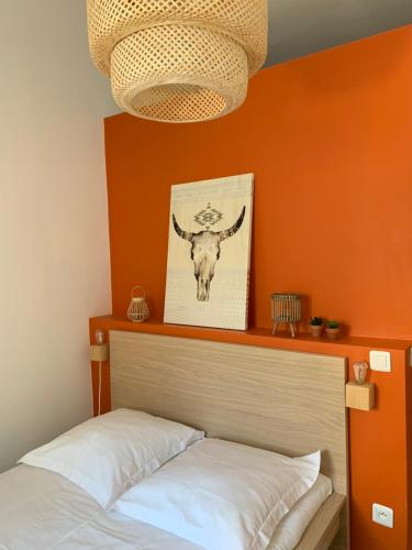 une chambre avec un mur orange avec un lit et une image d'un taureau dans l'établissement JOOLIA SooHome, à Marseille