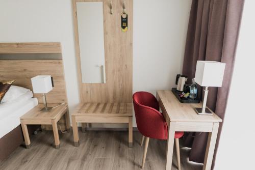 a bedroom with a desk and a bed and a red chair at Hotel Duus by Keflavik Airport in Keflavík
