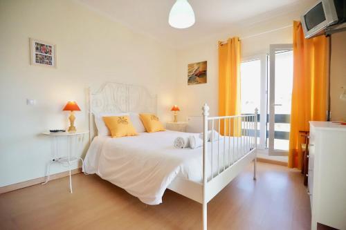 a bedroom with a white bed with orange curtains at The Wavecatcher - Deluxe Flat - Baleal / Peniche in Ferrel