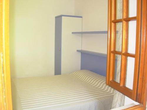 um pequeno quarto com uma cama e uma janela em Appartamento Il Nespolo em Pomonte