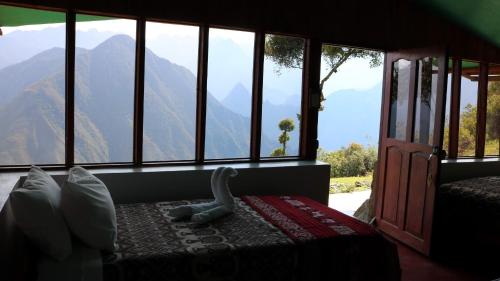 a bedroom with a large window with mountains in the background at Llactapata Lodge overlooking Machu Picchu - camping - restaurant in Salcantay