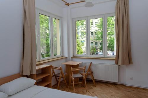 a bedroom with a table and chairs and windows at Casa Rezidentiala Pasteur in Cluj-Napoca