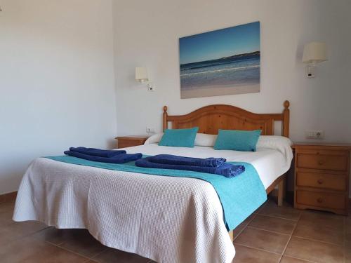 a bedroom with a bed with blue pillows on it at Apartamentos Marivent in Cala en Blanes