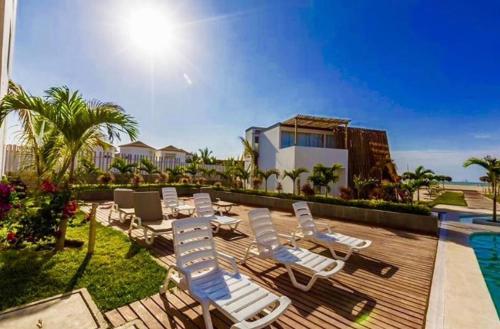 a deck with lounge chairs and a swimming pool at Palmeras de Bocapan, Tumbes in Zorritos