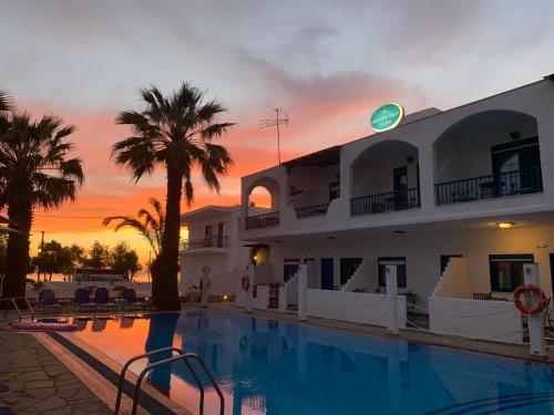 a hotel with a swimming pool in front of a sunset at Ariadni Blue in Neos Marmaras