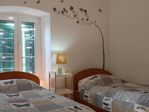 a bedroom with two beds and a tree on the wall at Apartments Jerko in Primošten