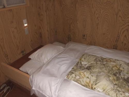 1 cama no hecha con sábanas y almohadas blancas en Guesthouse Otaru Wanokaze single room / Vacation STAY 32196 en Otaru