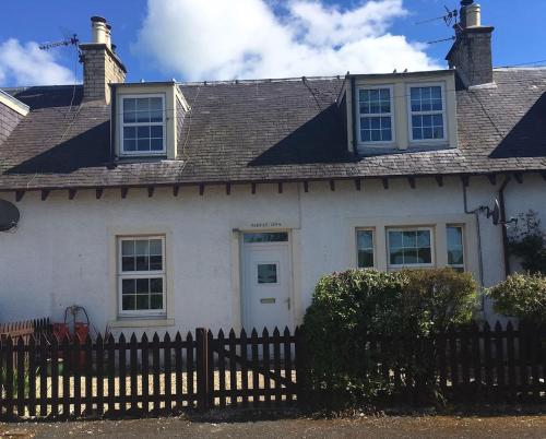 a white house with a fence in front of it at Herb Wood Cottage in Hawick