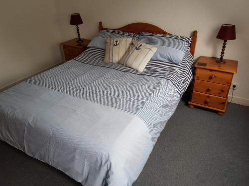 un lit avec des draps et des oreillers à rayures bleues et blanches dans l'établissement Marina Apartment, à La Forêt-Fouesnant