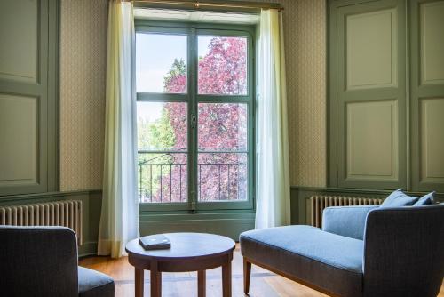a living room with a blue couch and a window at Schloss Schadau - Swiss Historic Hotel in Thun
