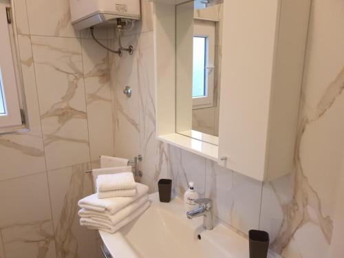 a bathroom with a sink and a mirror and towels at Mar e Sol Apartments in Hvar