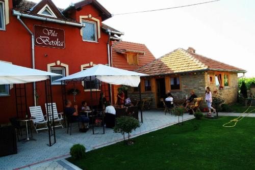 a group of people sitting at tables outside of a building at Vila Boska Palic in Palić