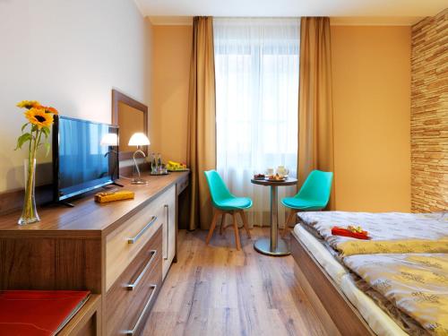 a bedroom with a bed and a desk with a television at Hotel Viktor in Bratislava
