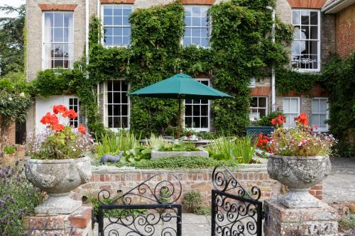 a garden with two benches and an umbrella at Rectory Manor in Lavenham
