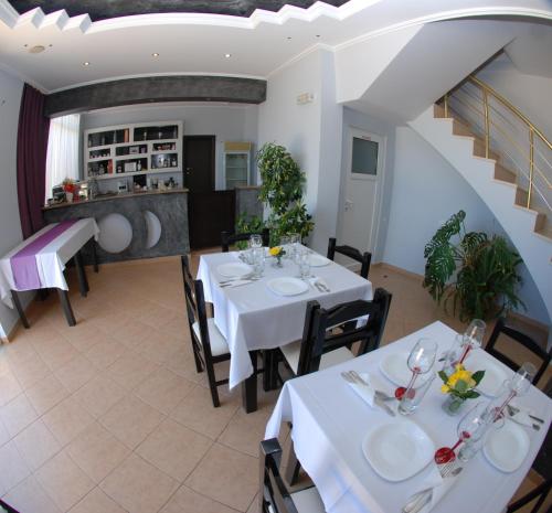una sala da pranzo con tavoli e sedie bianchi di Villa Doka a Sarandë
