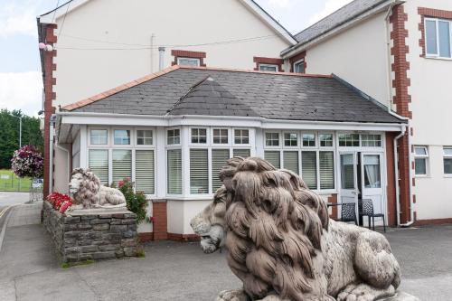 uma estátua de um leão em frente a uma casa em The Masons Arms Hotel em Bridgend