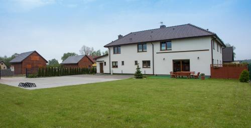 a large white house with a grass yard at Bałtyk Park Gąski in Gąski