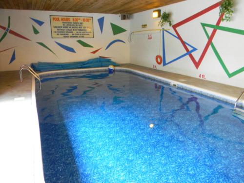 a swimming pool in a building with a painting on the wall at Beachside Motel in Penticton