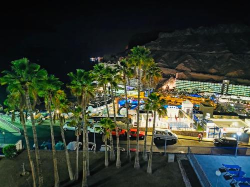 a view of a harbor with palm trees at night at apartmant Adrian Vista Taurito in Taurito