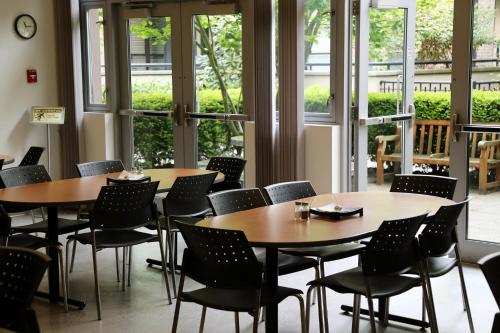 a dining room with tables and chairs and windows at Carey Centre on UBC campus in Vancouver