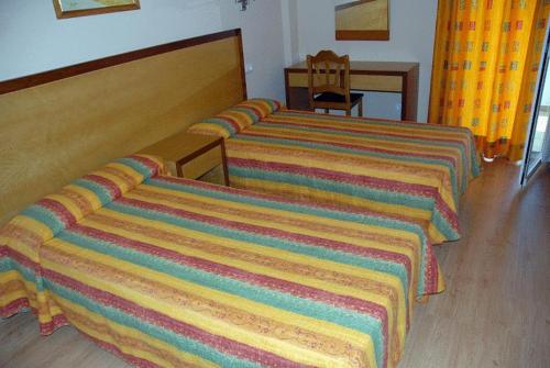 two beds in a hotel room with colorful blankets at Apartamentos Martha's in Palmanova