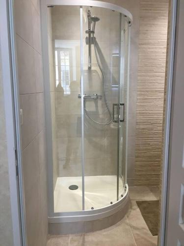 une douche avec une porte vitrée dans une salle de bain dans l'établissement Chez Maufoux - Centre - Hospices - Climatisation, à Beaune