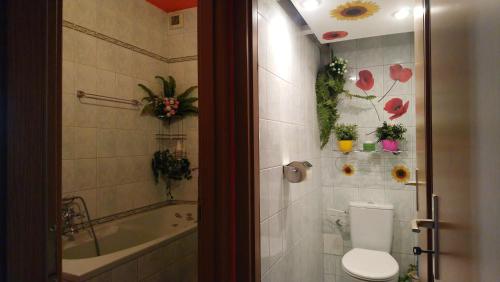 a bathroom with a toilet and a tub with flowers on the wall at Apartmán Romance in Komárno