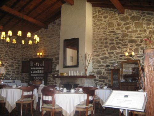 restauracja ze stołami i krzesłami oraz kamienną ścianą w obiekcie Pazo A Freiria w mieście Puebla de Trives