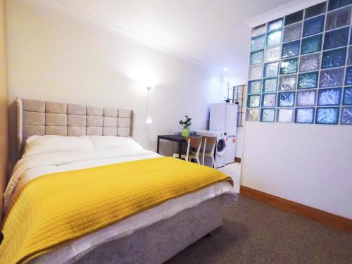 um quarto com uma cama com um cobertor amarelo em Flat 1 at 6 Taunton Mews em Londres