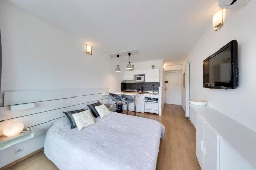 een witte slaapkamer met een bed en een televisie bij Studio la Plage in Roquebrune-Cap-Martin