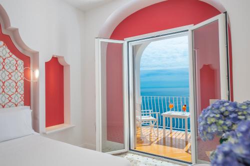 a room with a window and a balcony with a view of the ocean at Tramonto d'Oro in Praiano