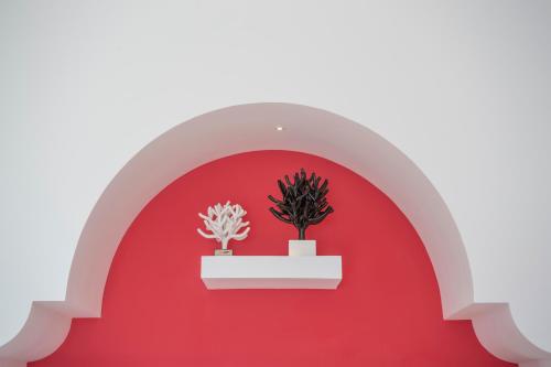 a red wall with two potted plants on a shelf at Tramonto d'Oro in Praiano