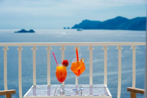 two cocktails sitting on a table on a balcony at Tramonto d'Oro in Praiano