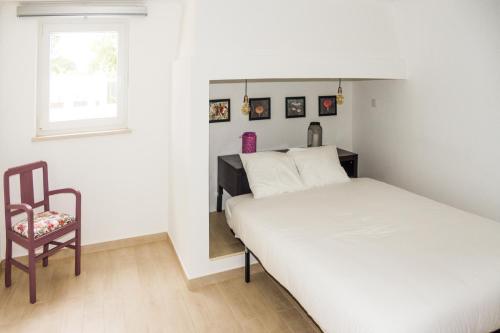 a small bedroom with a bed and a chair at Casa das Pipas Palmela #1 in Pinhal Novo