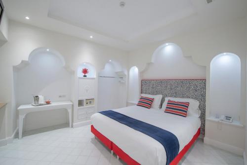 a white bedroom with a bed with red and blue pillows at Tramonto d'Oro in Praiano