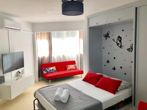 a bedroom with a red bed and a red couch at Studio in The Center of Torremolinos in Torremolinos