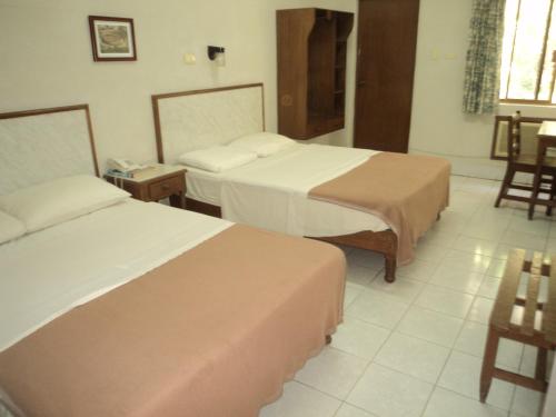 a hotel room with two beds and a table at Hotel Kuraica in Ciudad Obregón