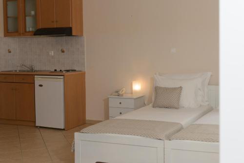a bedroom with a white bed and a kitchen at So Nice Hotel in Marathokampos