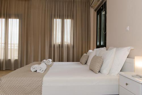 a bedroom with a large white bed with towels on it at So Nice Hotel in Marathokampos