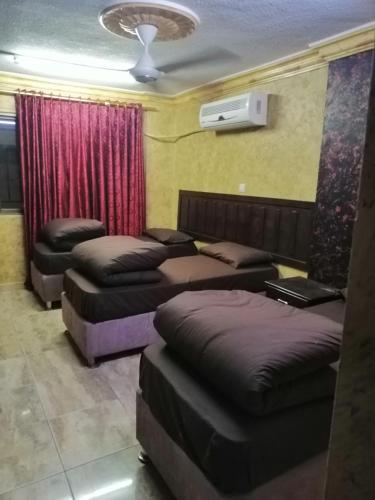 a room with three beds and a fan and avertisement at Aqaba Roza in Aqaba