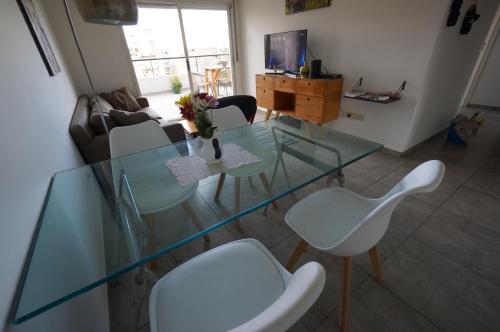 sala de estar con mesa de cristal y sillas blancas en Ático Palermo en Buenos Aires