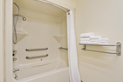 La salle de bains est pourvue d'une douche et de serviettes sur une étagère. dans l'établissement Baymont by Wyndham Santee, à Santee