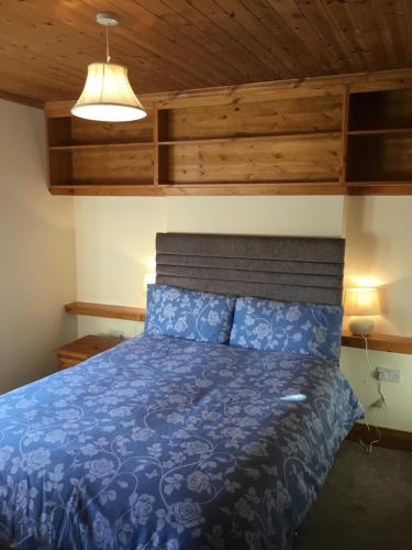 a bedroom with a blue bed with a wooden ceiling at St Judes House in Killarney