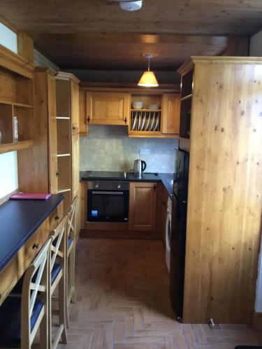 a kitchen with wooden cabinets and a black refrigerator at St Judes House in Killarney
