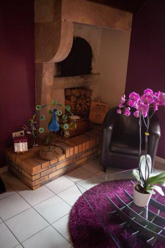 a living room with a fireplace and a couch and flowers at Relais Vosgien - Hôtel Restaurant "la Table de Sophia" in Saint-Pierremont