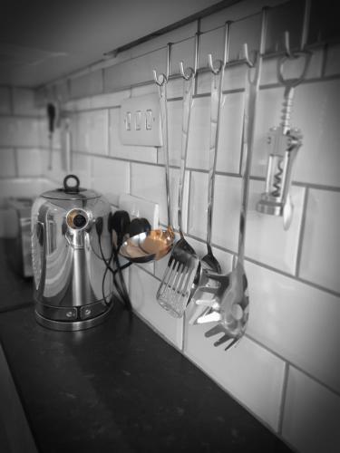 a kitchen counter with utensils hanging on a wall at Luxurious Luton town center flat with free parking in Luton