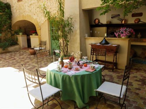 een tafel met een groene tafelkleed en stoelen bij Le Térébinthe B&B in Lauris