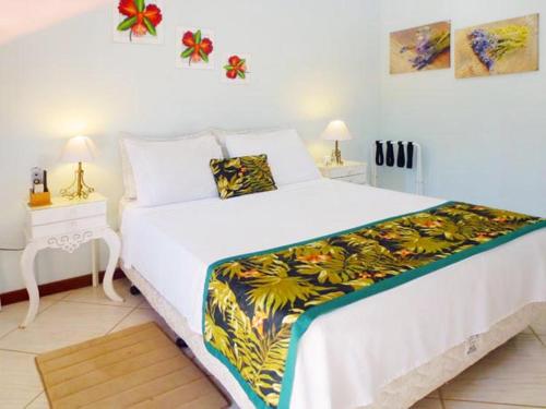 een slaapkamer met een groot wit bed en een kleurrijke deken bij Pousada Horizonte dos Borbas in Abraão