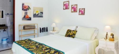 a white bedroom with a bed and pictures on the wall at Pousada Horizonte dos Borbas in Abraão